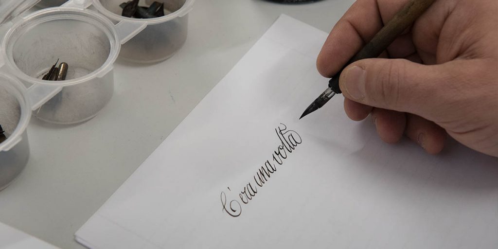 Partecipante a un workshop di calligrafia a Milano mentre scrive con pennino e inchiostro