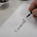 Partecipante a un workshop di calligrafia a Milano mentre scrive con pennino e inchiostro